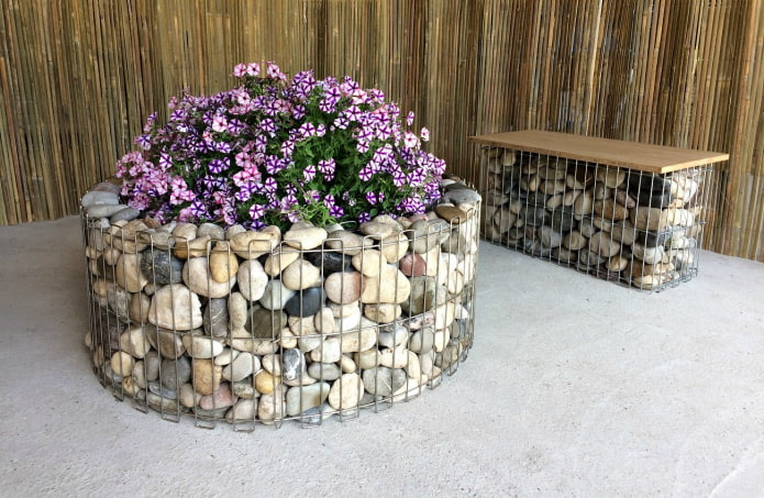 parterre de fleurs rond avec une bordure de pierres colorées dans un cadre en fil de fer