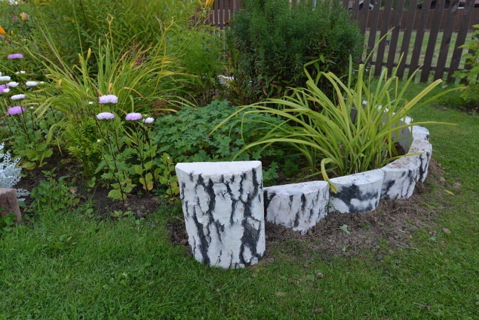 bordure pour un parterre de fleurs en fragments de bûches avec écorce blanchie à la chaux