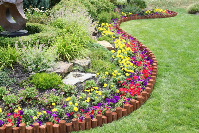 une bordure pour un jardin de fleurs faite de piquets enfoncés à différentes profondeurs