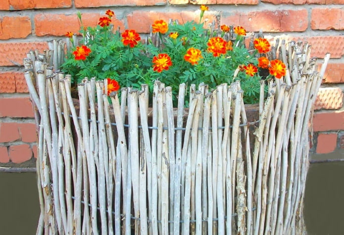 décoration des côtés de la plate-bande avec de fines branches, insérées verticalement dans le fil de fer