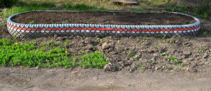 parterre de fleurs ovale avec une bordure de coupe de pneus et de bande de roulement peinte