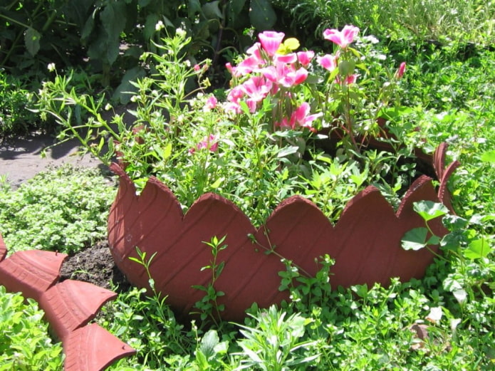 un parterre de fleurs avec une jante bouclée faite d'un pneu peint pour ressembler à un pot en argile