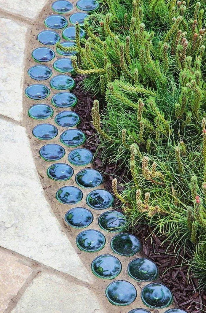 bordure pour un parterre de fleurs à partir de fonds de bouteilles en verre noyées dans du ciment